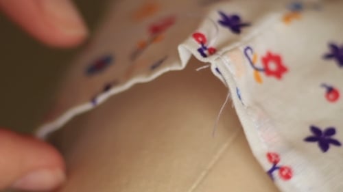 Hands Sewing Floral Fabric onto Plain Fabric