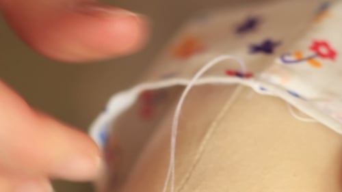 Hands Sewing Fabric with Needle and Thread