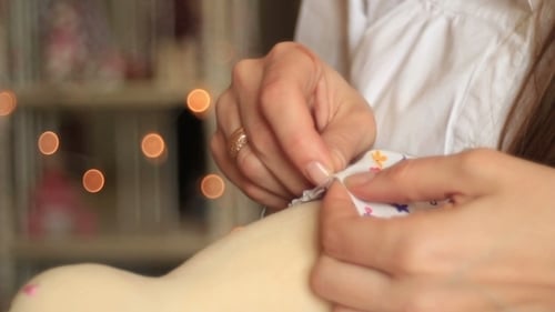 Person Sewing Fabric onto Handmade Doll Close Up