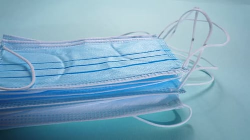 Stack of Disposable Face Masks on Blue Surface