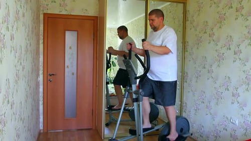 Overweight Man Exercising On Trainer Ellipsoid