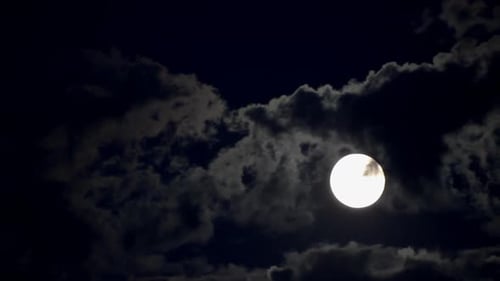 Full Moon Shining Brightly Through Dark Cloudy Sky