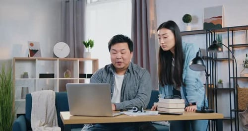 Chinese Man and Woman Working Together on Business Project on Computer