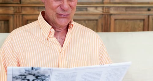 Homem sênior lendo jornal na sala de estar