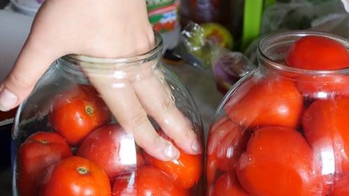 Filling Glass Jars With Red Tomatoes