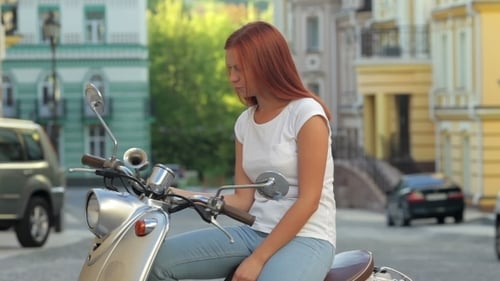 Fille assise sur un scooter dans la ville européenne