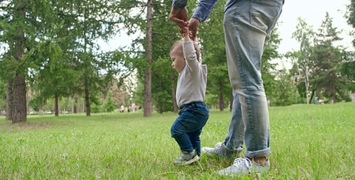 Infant Learning to Walk with Parent in Park