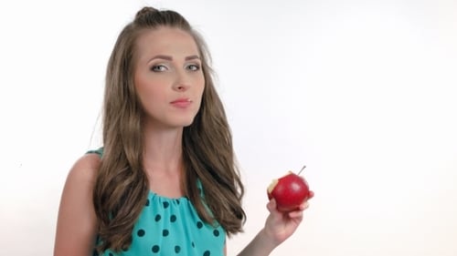 Young Woman Eating a Red Apple in Studio