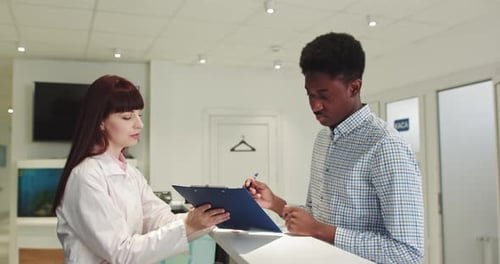 Handsome Young African American Man Fill The Form At The Reception In Clinic