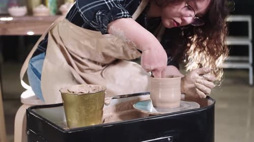 Woman shaping clay on a pottery wheel