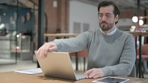Junger Mann schließt Laptop und verlässt das Café