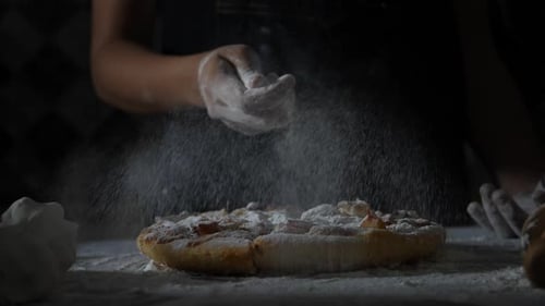 Slow motion of woman hands sifting flour on pizza