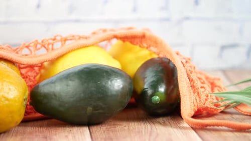 Fruta fresca de naranja y aguacate en una bolsa de la compra en la mesa
