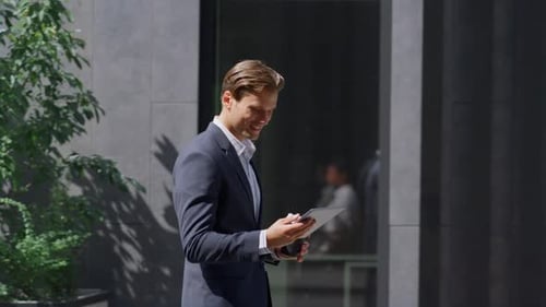 Smiling Man in Suit Using Tablet Outdoors