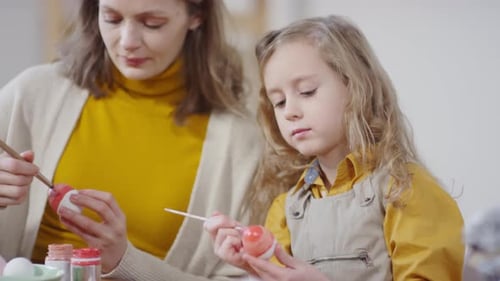 Girl Decorating Easter Egg and Smiling for Camera
