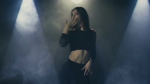 Schöne junge Frau tanzt Hip-Hop auf der Bühne In Lichtstrahlen Und Im Rauch