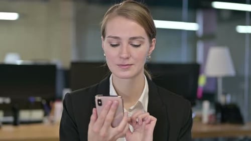 Young Blonde Woman Uses Mobile Phone in Office