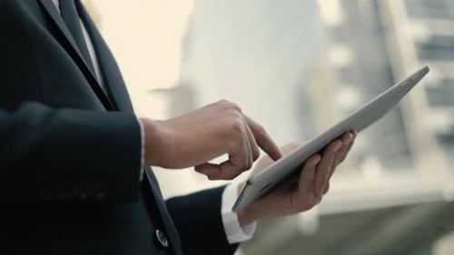 Close-up portrait a creative businessman in a black suit using his tablet typing message.
