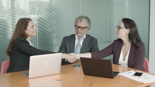 Teamwork in Modern Office with Laptops and Handshake