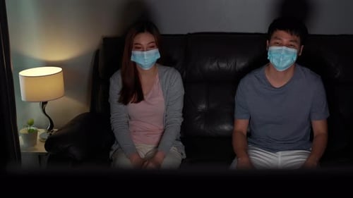 Couple Wearing Masks Watching TV at Night
