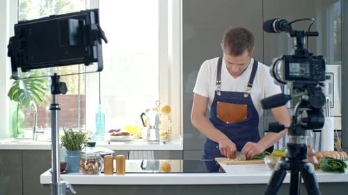 Young Man Cooking and Recording in Kitchen