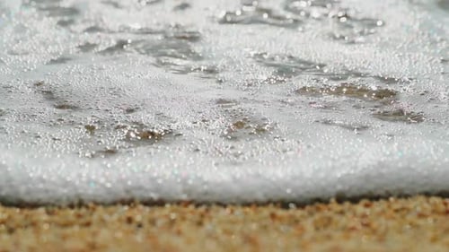 Closeup Slow Motion Footage of Beach of Gravel the Coarse Sand Waves Run on Sand Wet Stones Glint in