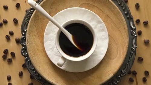 Top View of Coffee with Spoon on Decorative Plate on Wooden Table