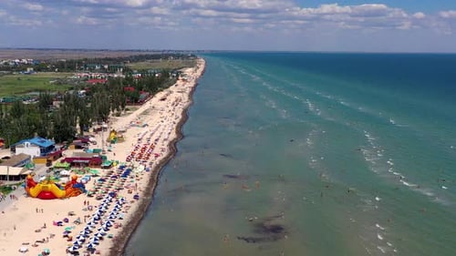 Beautiful flight in summer over the beach. People are resting near the sea.
