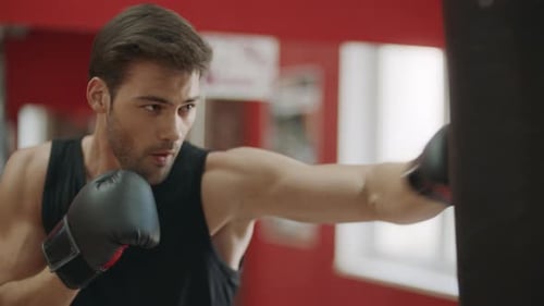 Kickboxer Man Training Punches on Combat Bag in Fight Club