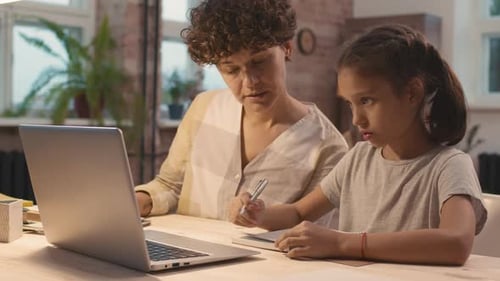 Woman Helping Child with Homework Using Laptop