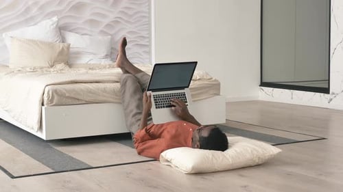 Lazy AfricanAmerican Man Works on Laptop Lying on Floor