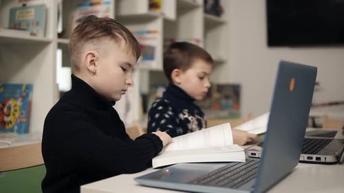 Young Boys Studying with Books and Laptops