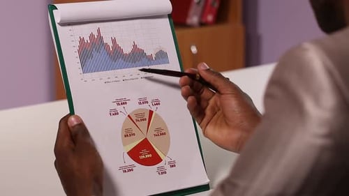 Adult Analyzing Business Data on Clipboard
