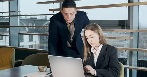 Portrait of a Man and a Woman Discussing Work with Notebook in the Brightly Lit Modern Office