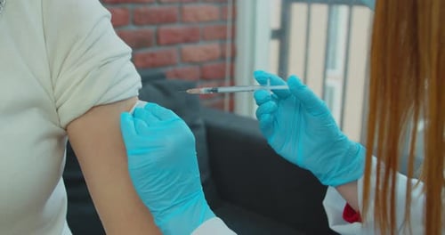 Close Up Female Doctor Wearing Mask Giving Vaccination To Senior Woman at Home