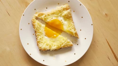 Top View of Toast with Fried Egg and Cheese on Wooden Kitchen Table