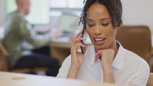 Happy african american businesswoman talking on smartphone in creative office