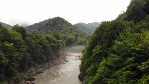 Flying over the mountain river with fog.