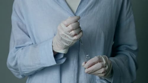 Gloved Hands Preparing Syringe Injection From Vial
