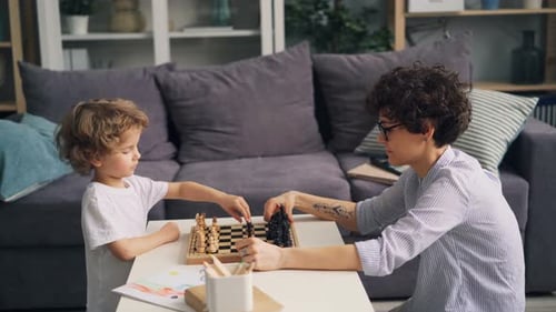 Child and Woman Playing Chess Together at Home