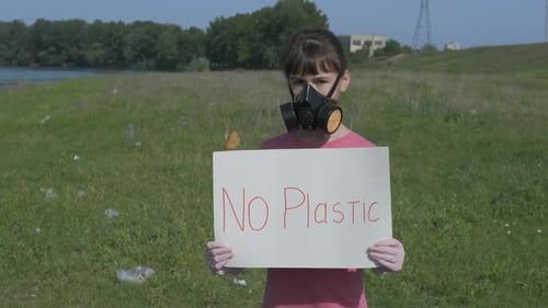 Teenager Holding "No Plastic" Sign in Polluted Field
