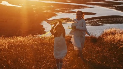 Young Mother with Her Daughter in White Clothes Running on the Hill and Playing with the Kite at