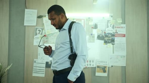 Pensive Detective Holding Glasses Near Evidence Board