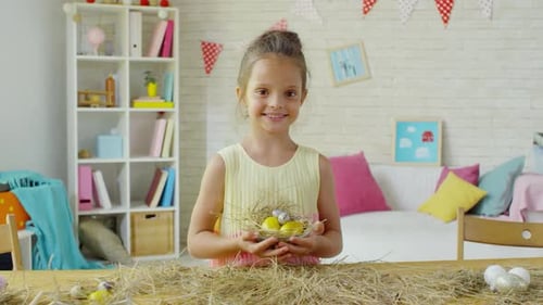 Happy Little Girl Posing with Easter Eggs in Hay Nest
