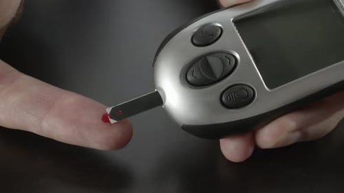 Droplet of Blood Being Fed into Glucose Meter