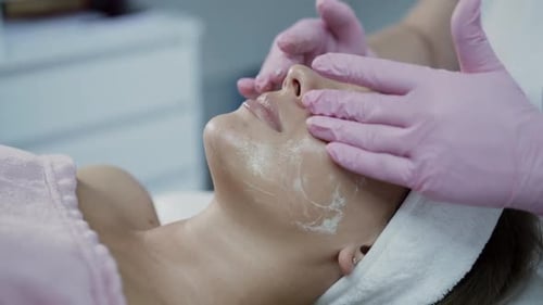 Beautician's Hands Rub the Cleansing Foam Into Female Face in Cosmetology Clinic