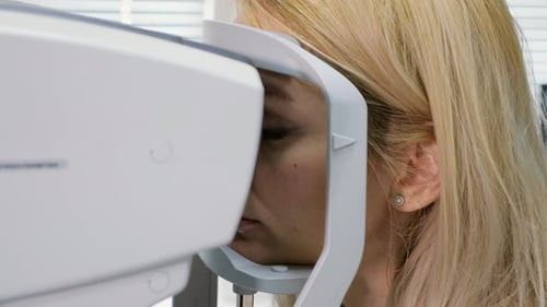 Frau blickt auf Refraktometer-Augentestmaschine in der Augenheilkunde