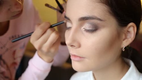 El maquillador hace que una chica sea un hermoso maquillaje