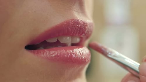 Maskenbildnerin malt die Lippen eines schönen lächelnden Mädchens