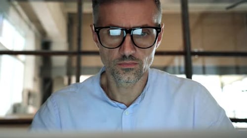 Focused Man in Glasses Working at Computer